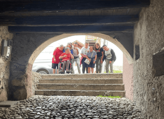 Gruppo del CSO della Cooperativa Il Piccolo Principe in gita inclusiva a San Martino di Castrozza, fotografati insieme sotto un arco di pietra