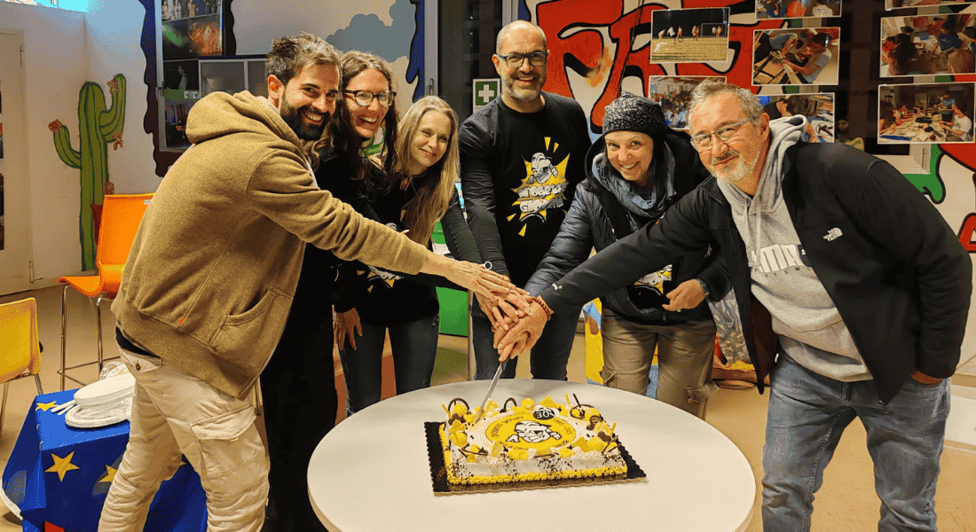 Staff del Progetto Giovani Casarsa mentre taglia la torta dei 30 anni nella sede con murales