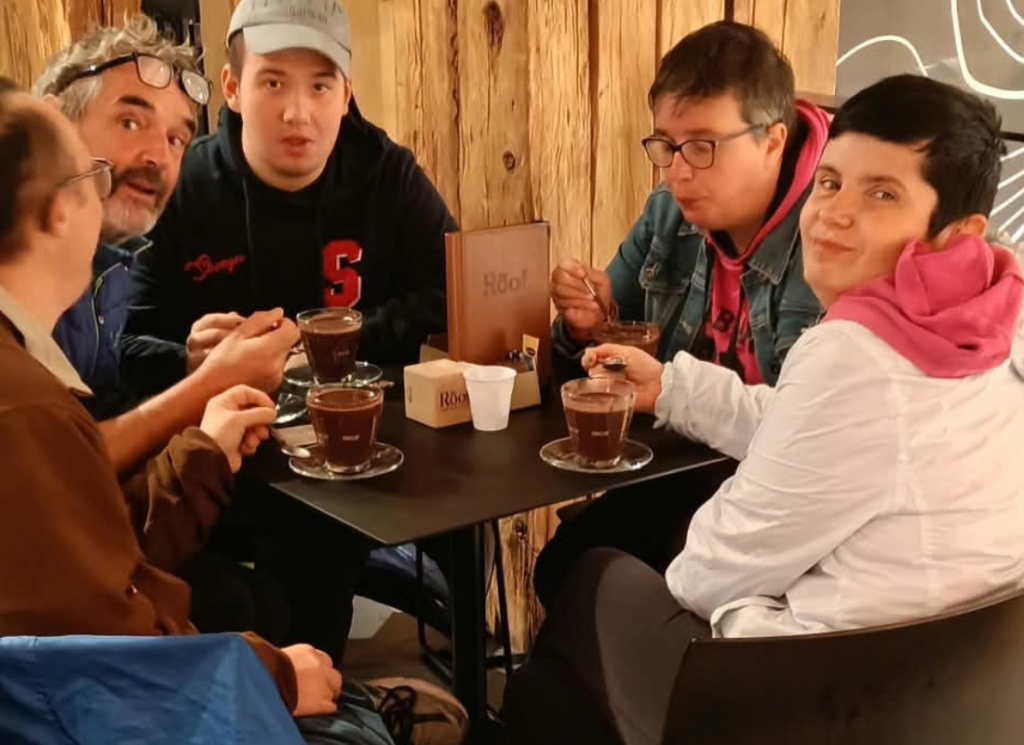 Partecipanti e accompagnatori della UET «Il Casale» seduti intorno a un tavolo mentre bevono qualcosa di caldo durante il soggiorno ad Auronzo.
