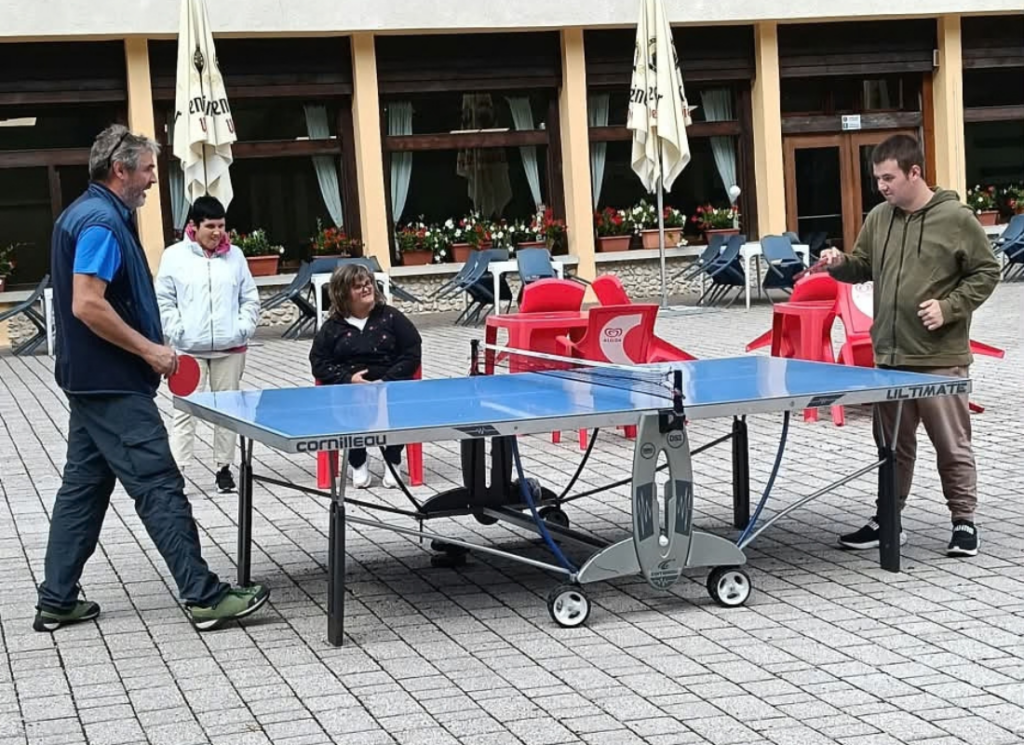 Alcuni partecipanti e accompagnatori della UET «Il Casale» condividono una pausa intorno a un tavolo. La foto mostra uno dei momenti di vita di gruppo dei tre giorni trascorsi ad Auronzo di Cadore.